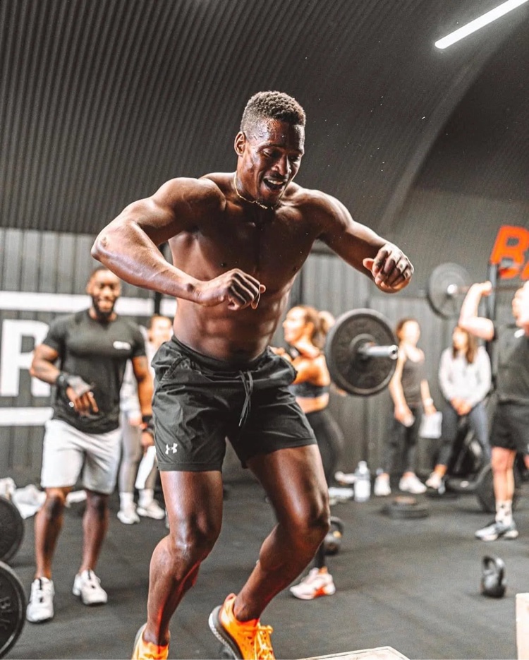 Movesharpish training shirtless in a gym, wearing black shorts and orange shoes